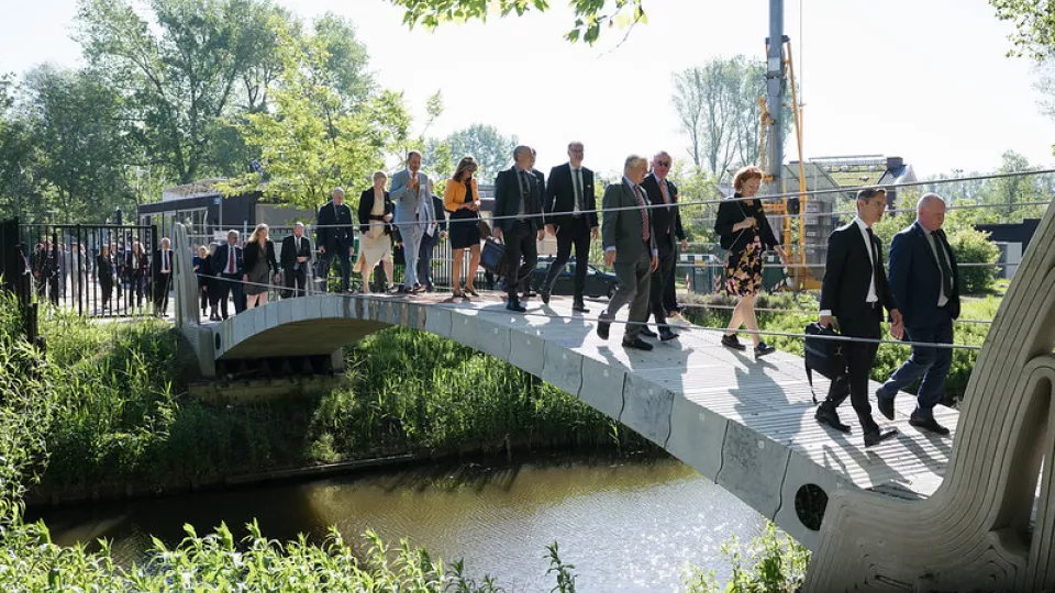 Photo of people crossing a bridge in summer daylight.